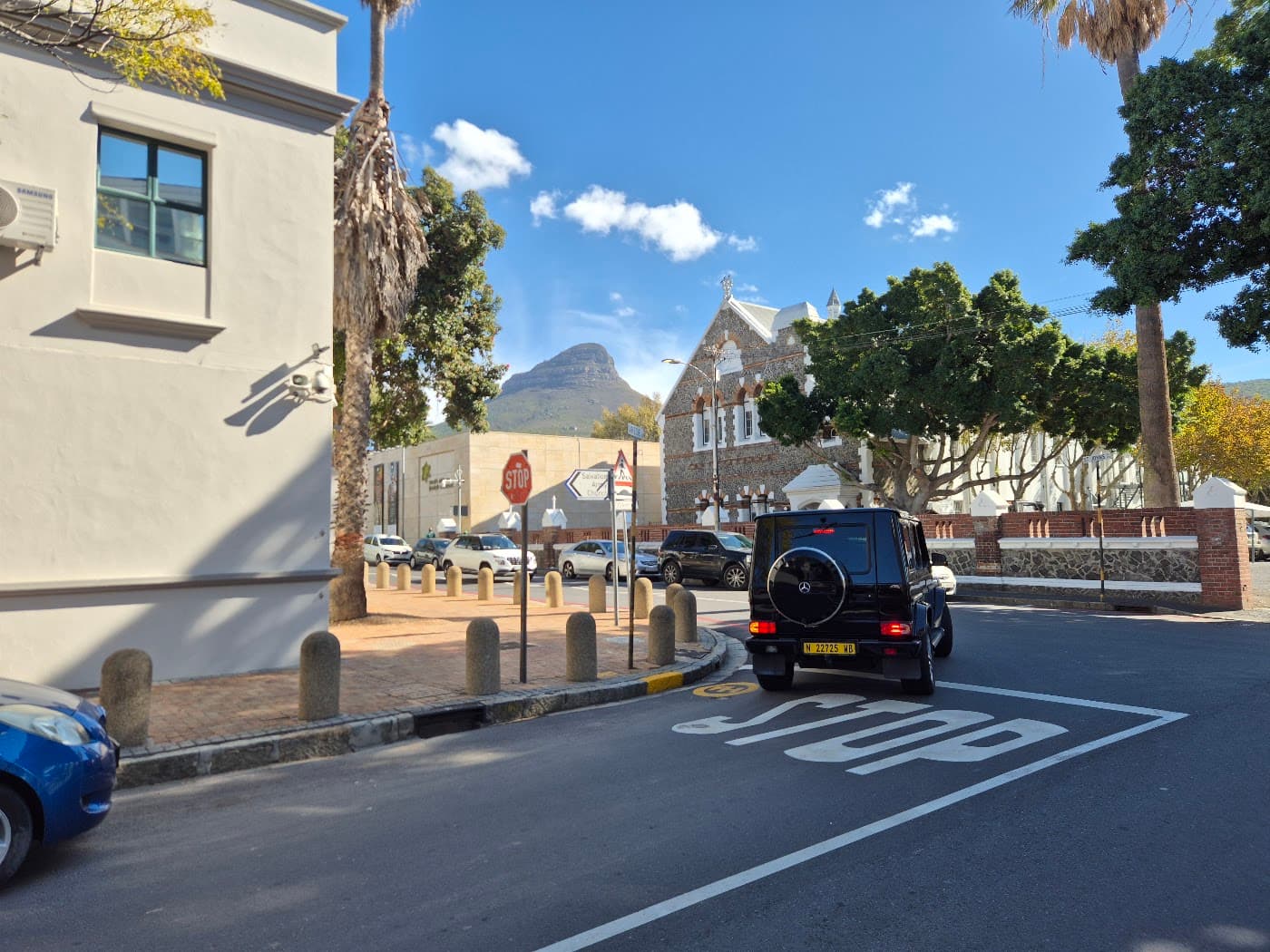 A street on the Atlantic Seaboard with an expensive SUV parked near a church, Lion's Head in the background