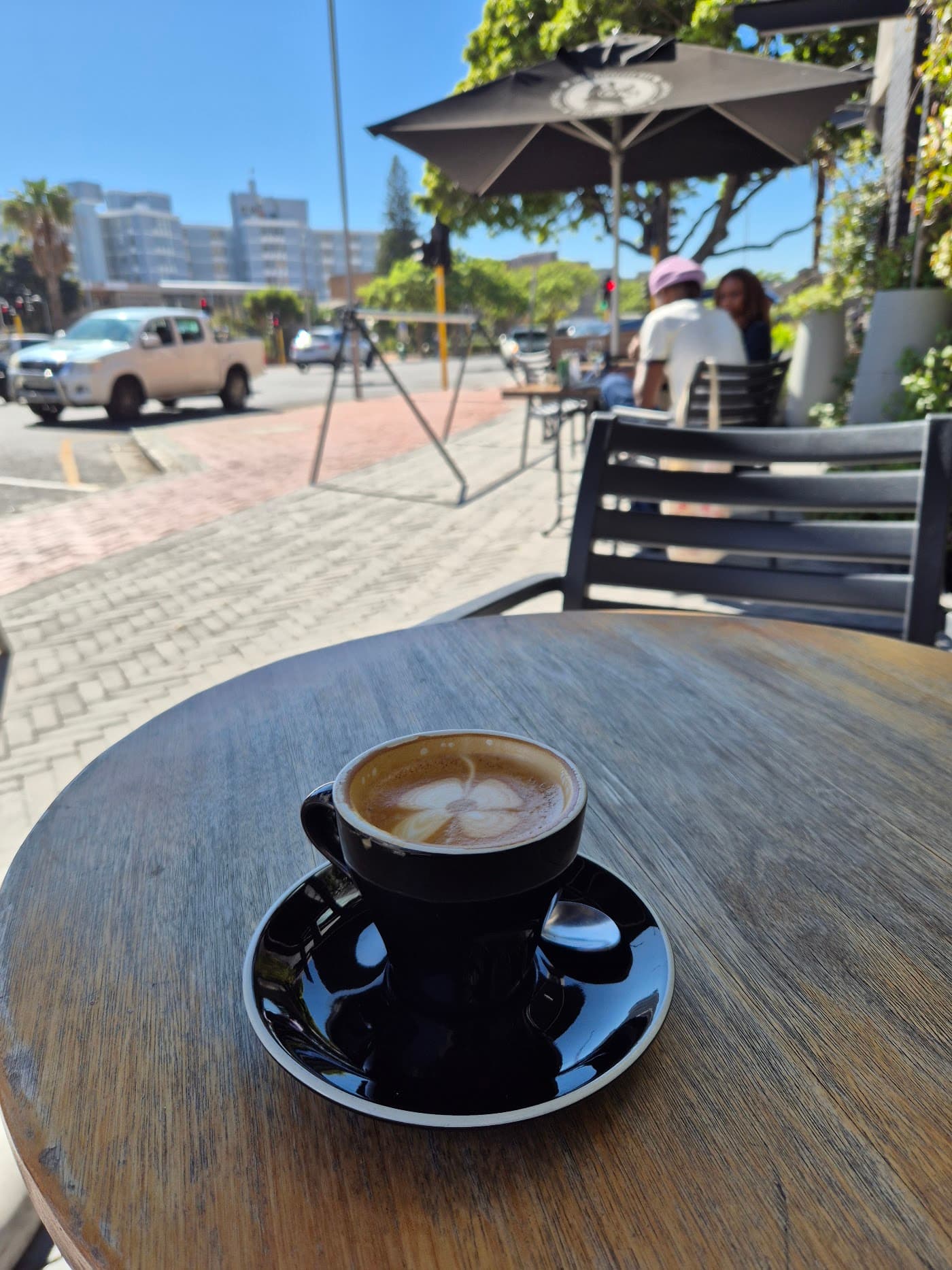 A flat white on a wooden table at an outdoor cafe along the Atlantic Seaboard