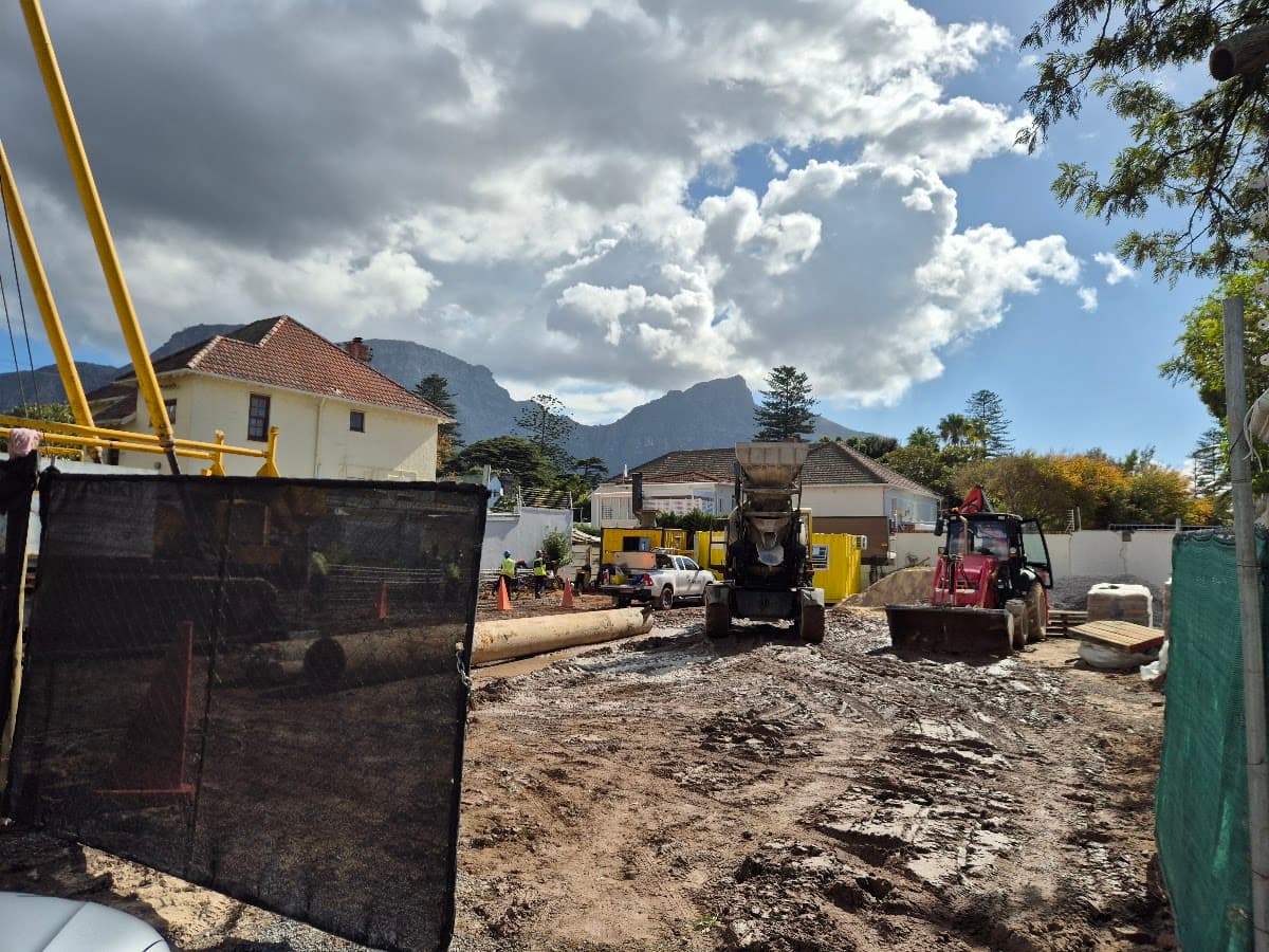 A construction site with an excavator and a mountain backdrop