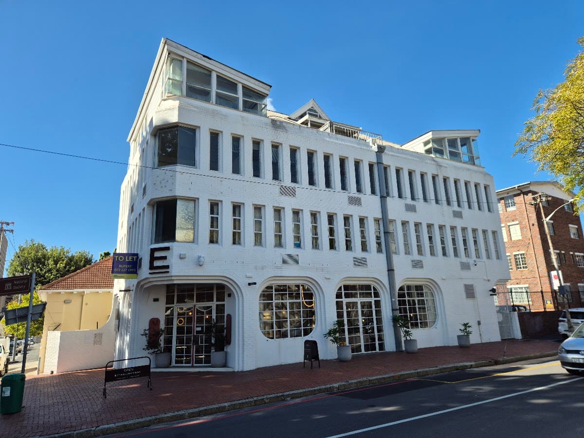 A restored white heritage building with ground-floor shopfronts