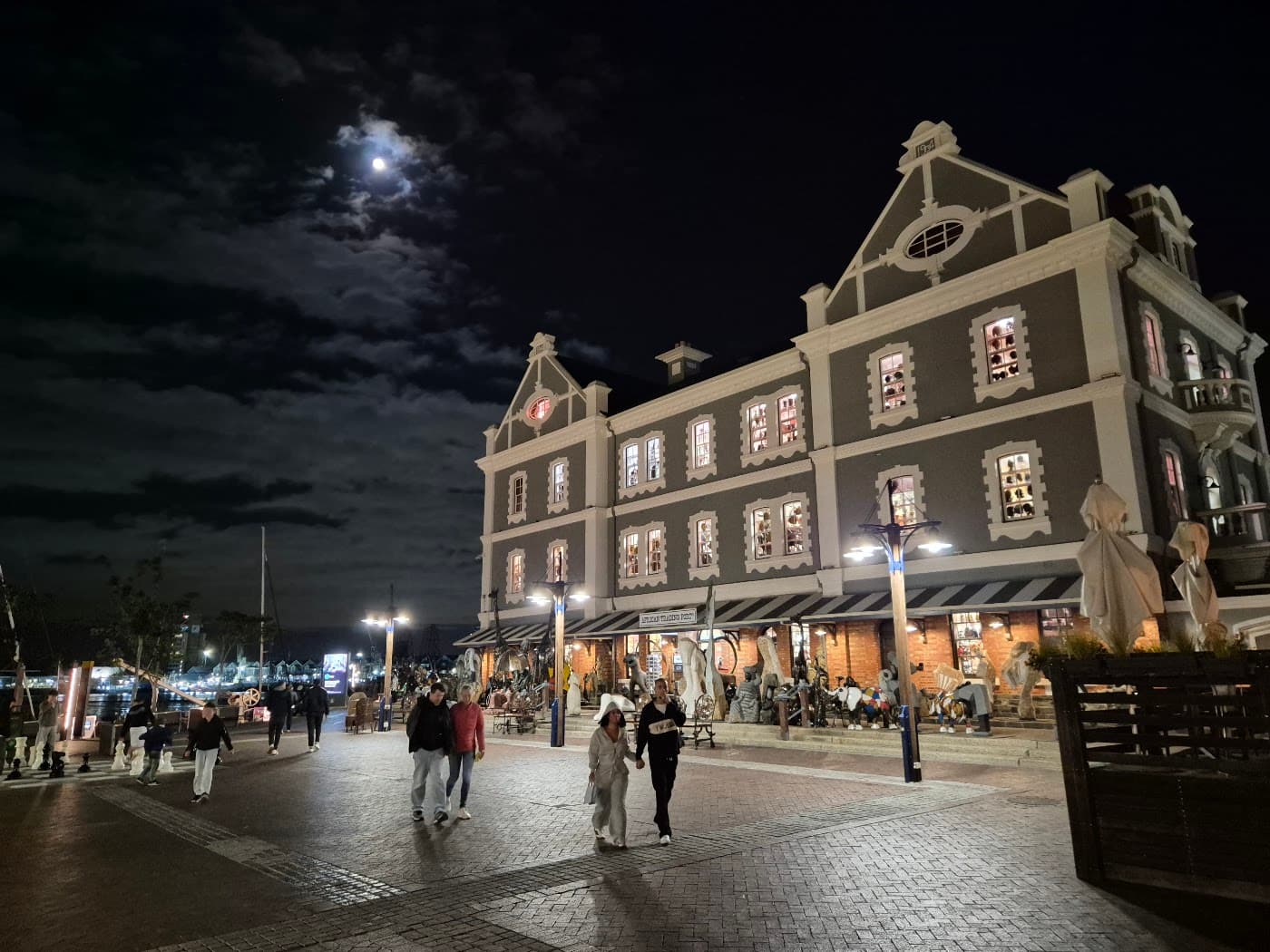 The V&A Waterfront at night, a historic building lit up with people walking past